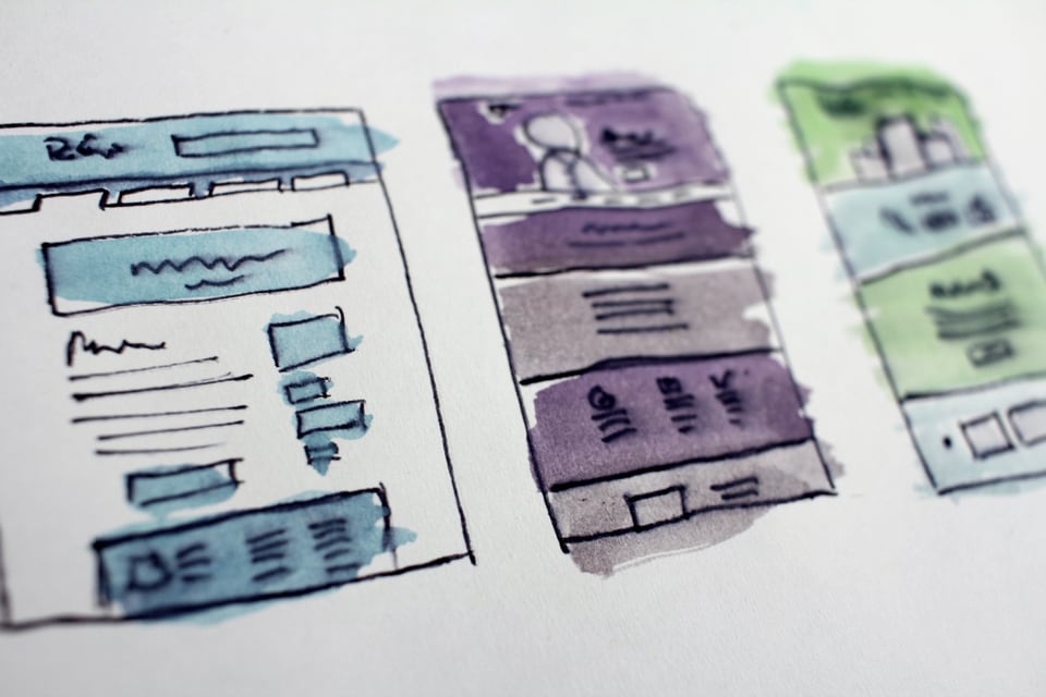 Watercolor sketches of website layouts on paper